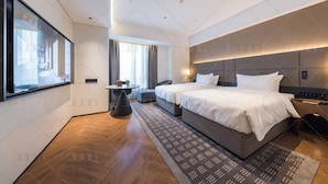 Een moderne hotelkamer met een groot bed, nachtkastjes, een bureau en uitzicht op de stad.