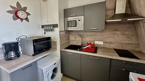 A compact kitchen with a microwave, oven, coffee maker, and a washing machine. - La mouette rieuse, terrace, sea view, beach access (Bernières-sur-Mer)