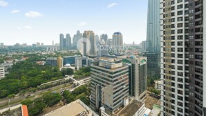A high-rise building with a modern glass facade, surrounded by other high-rise buildings and greenery.