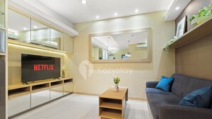 A modern living room with a flat-screen TV, a sofa, a coffee table, and a mirror on the wall.