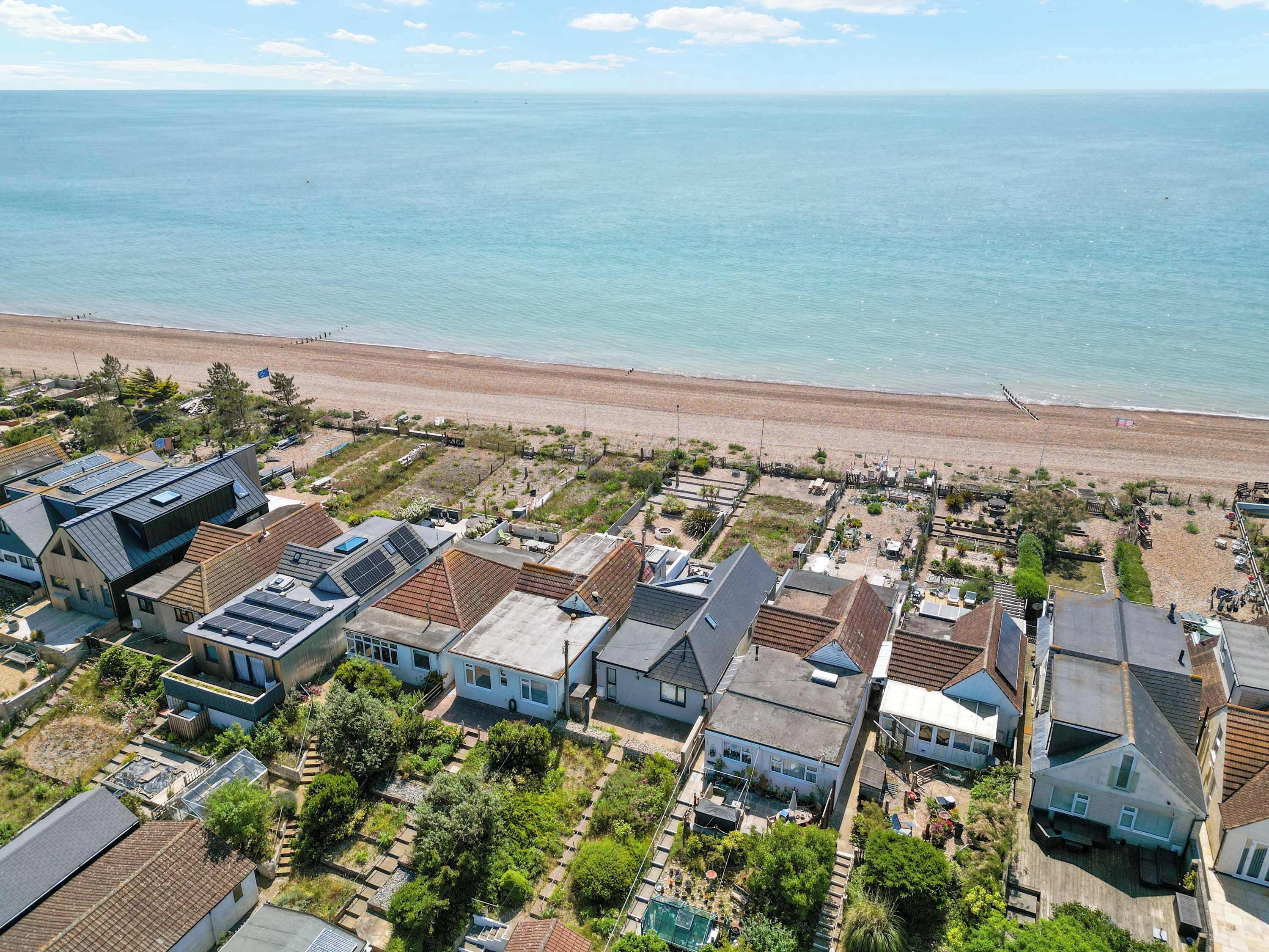 Zona residencial costera con casas, una playa y cielo despejado.
