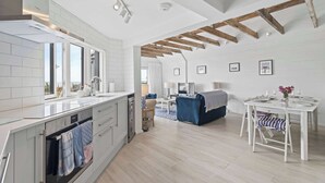 A modern kitchen with white cabinetry, a built-in oven, and a window overlooking the living area.
