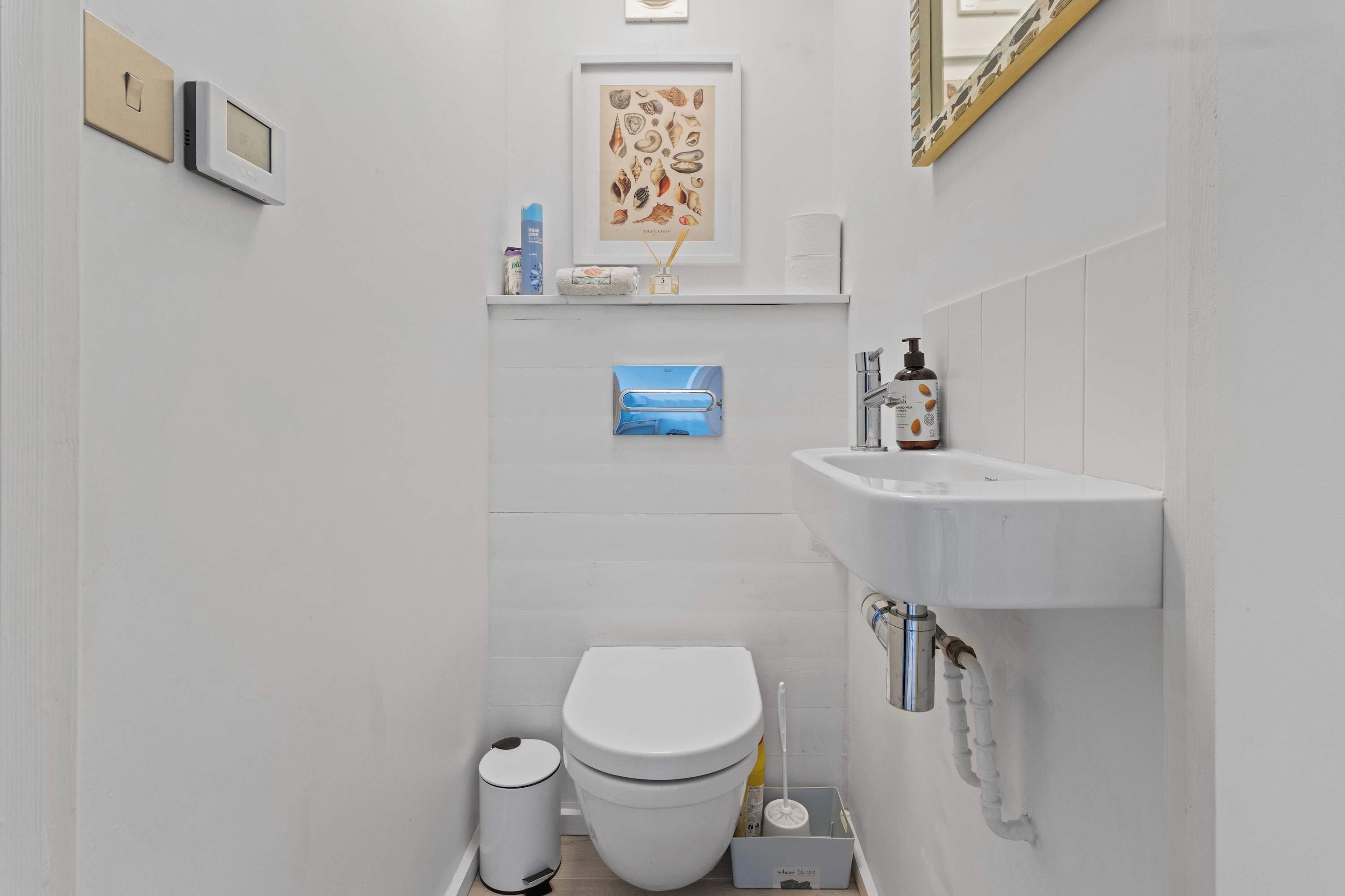 Un baño pequeño y moderno con inodoro, lavamanos y estantes de almacenamiento.