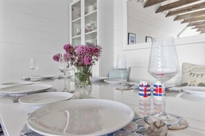 A dining table set with plates, glasses, and a vase of flowers.