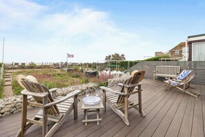 A wooden deck with two rocking chairs and a table with glasses and a tray. - Stunning Beachfront Bungalow  Ocean Views & BBQ (Pevensey Bay)