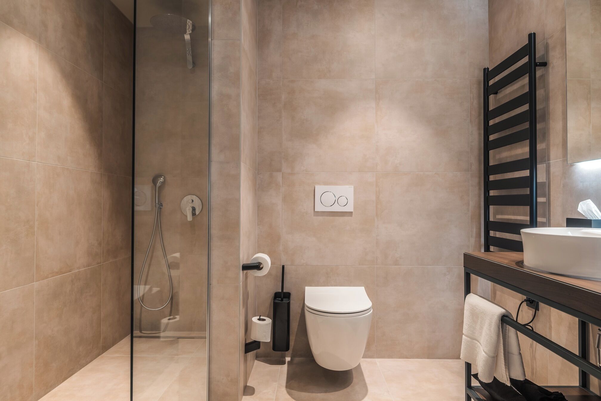 A modern bathroom with a glass shower enclosure, a toilet, a sink, and a towel rack.