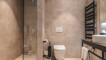 A modern bathroom with a glass shower enclosure, a toilet, a sink, and a towel rack.