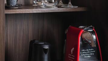 A coffee maker, a red tray with a coffee pot, and a red napkin on a wooden shelf.