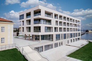 Ένα σύγχρονο, πολυώροφο κτίριο με μπαλκόνια, μεγάλα παράθυρα και θέα στη θάλασσα.