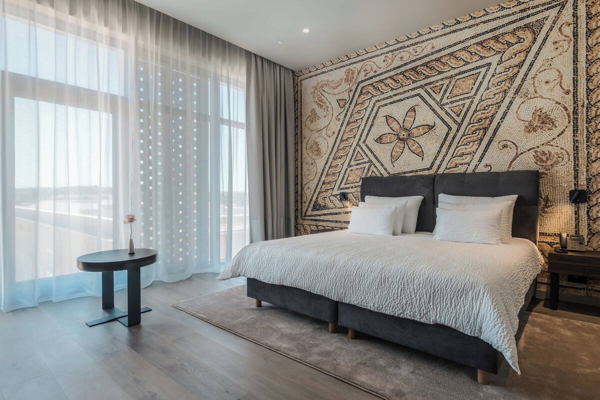 Une chambre moderne avec un grand lit, une petite table de chevet et un mur décoratif.