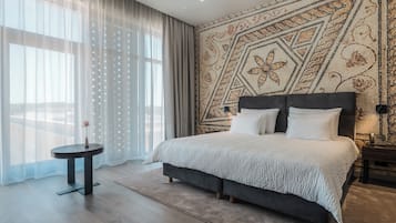 Quarto moderno com uma cama grande, uma mesinha de cabeceira e um detalhe decorativo na parede.