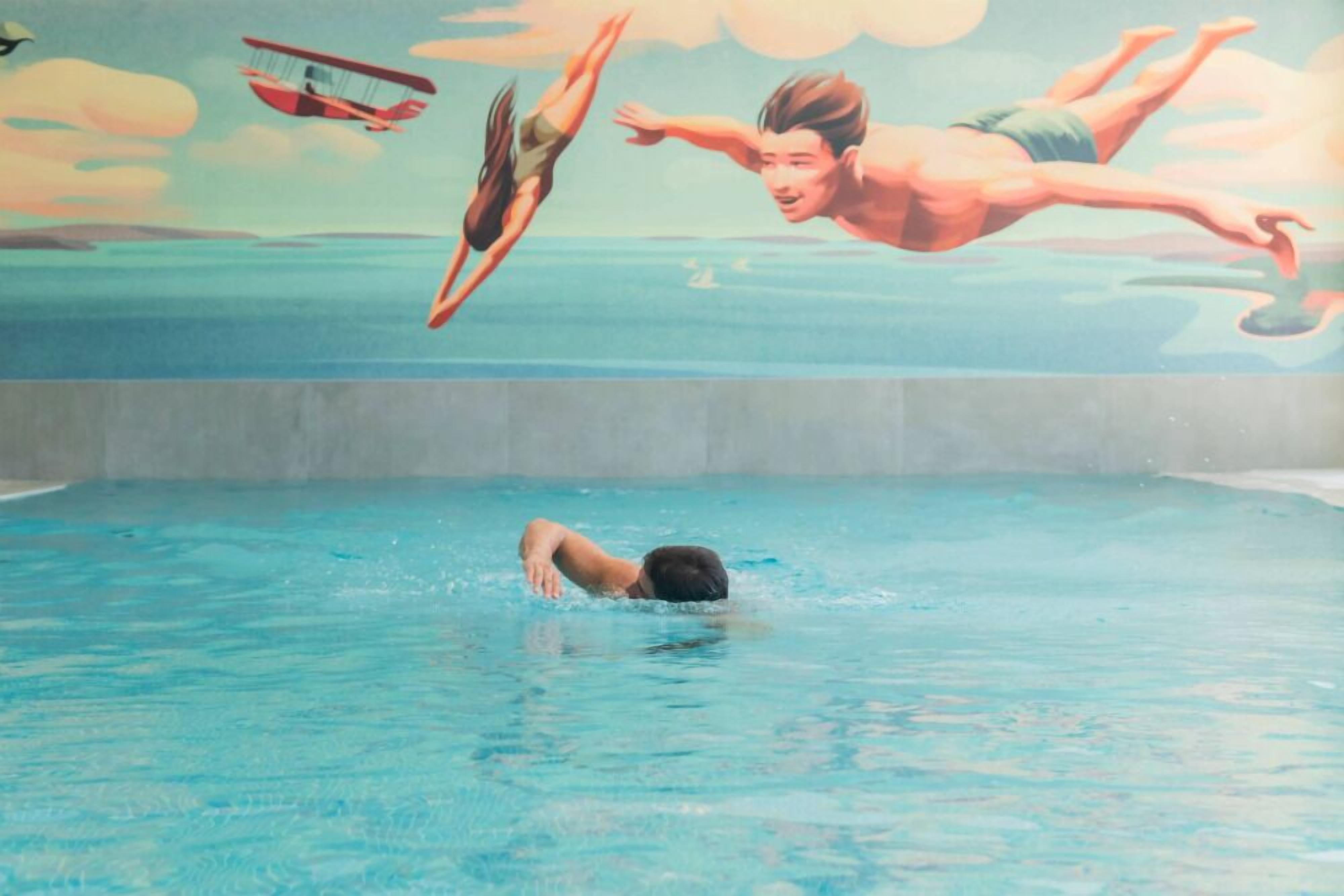 Una piscina con alguien sumergiéndose en el agua.