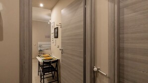 A narrow hallway with a wooden door on the right and a dining area with a table and chairs on the left. - Cerisola lovely studios in Rapallo (Rapallo)