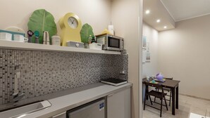 A compact kitchen with a microwave, kettle, and small refrigerator. A dining area with a table and chairs is visible in the background. - Cerisola lovely studios in Rapallo (Rapallo)