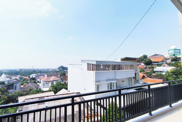 A residential building with a modern design, featuring a balcony with a black railing.
