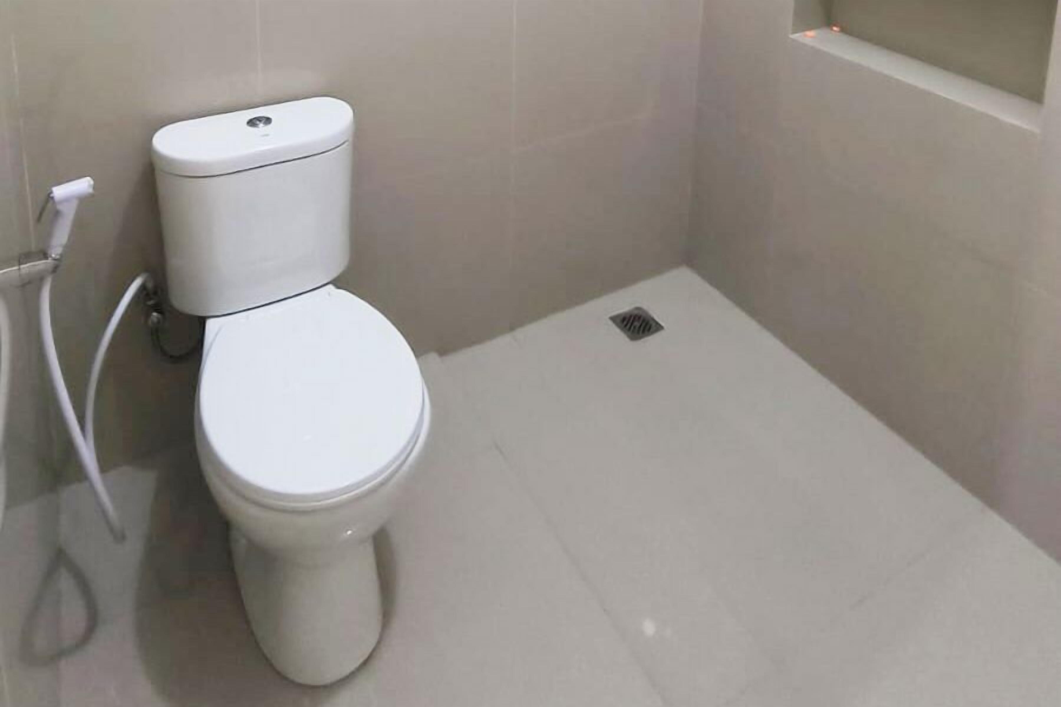 Et hvidt toilet i et badeværelse med flisegulv og -vægge.
