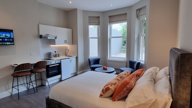 A modern hotel room with a large bed, a desk, and a seating area. - The Ivy Apartments (Bournemouth)