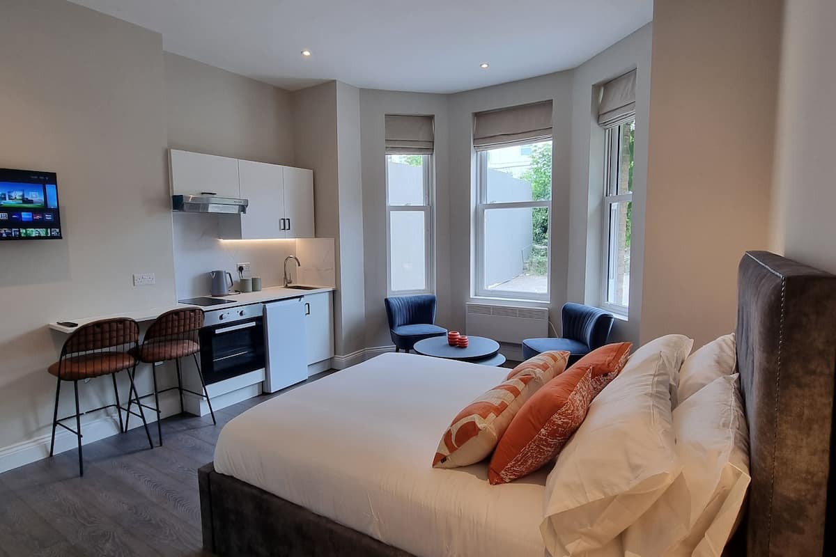 Quarto de hotel moderno com uma cama grande, uma mesa e uma área de estar.