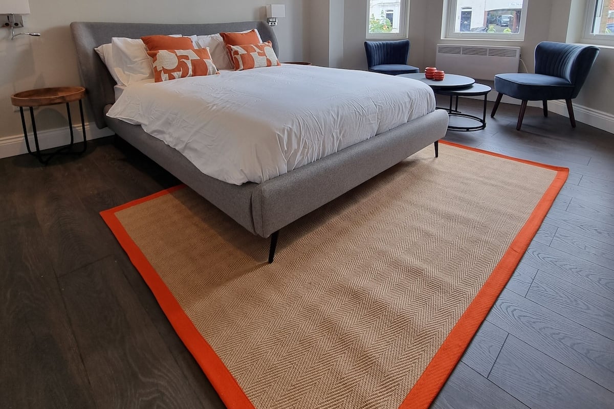 Quarto moderno com uma cama grande, uma mesinha e duas cadeiras.