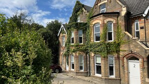 A Victorian-style building with brickwork and arched windows, surrounded by greenery. - The Ivy Apartments (Bournemouth)