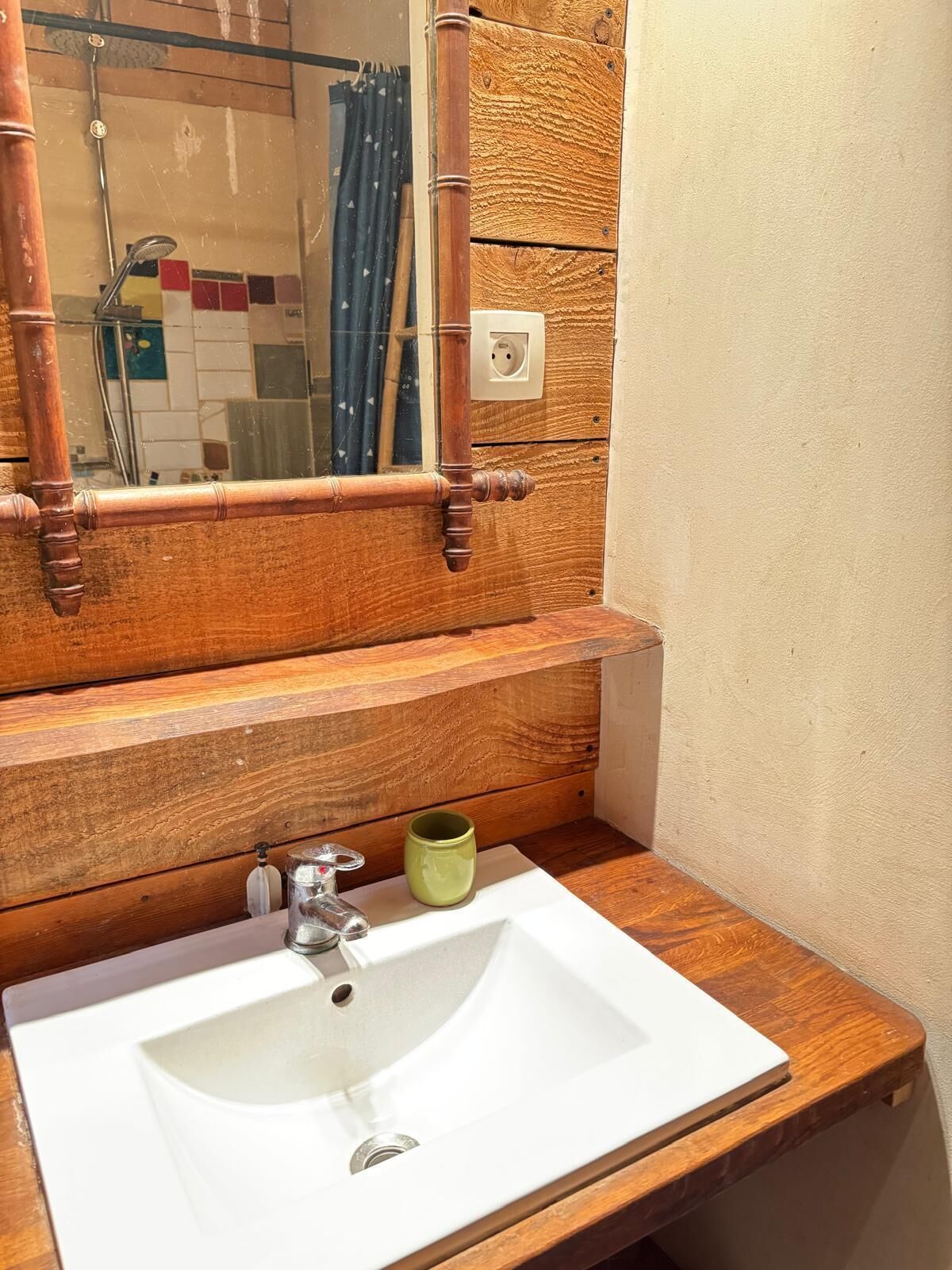 A bathroom with a wooden vanity, a white sink, and a mirror.