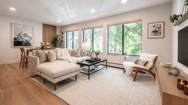 A modern living room with a sectional sofa, a coffee table, and a dining area with a chair and table.