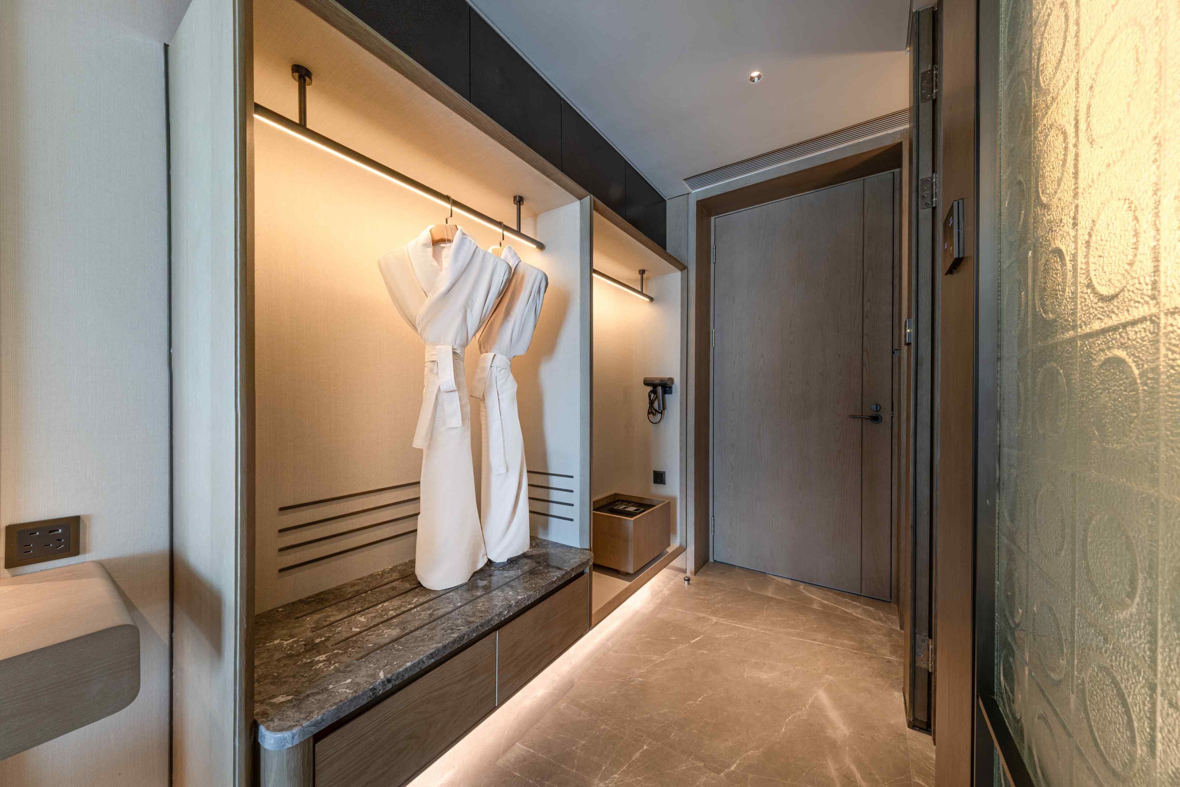 Un baño moderno con encimera de mármol, un perchero y una puerta de madera.