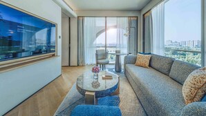 A modern hotel room with a large window, a sofa, a round coffee table, and a TV on the wall. - Nousland Beijing (Tongzhou)