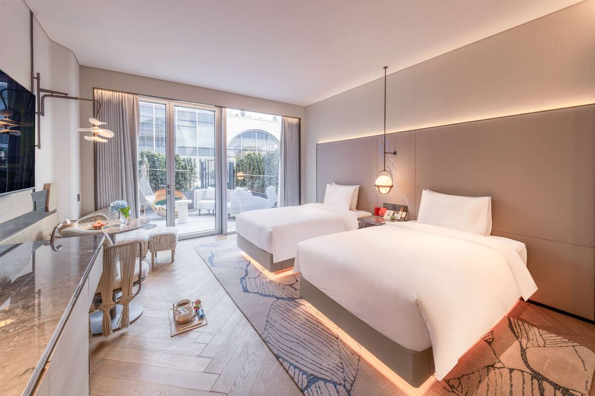A modern hotel room with a large bed, a desk, and a view of the outdoors.