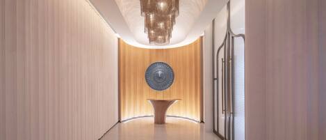 Un pasillo moderno con paneles de madera verticales, un elemento decorativo central en la pared y una lámpara de pie original.