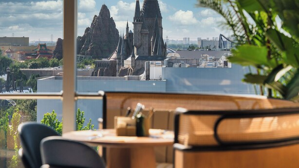 A view from a balcony with a table and chairs, overlooking a castle-like structure with multiple spires and a large rock formation. - Nousland Beijing (Tongzhou)