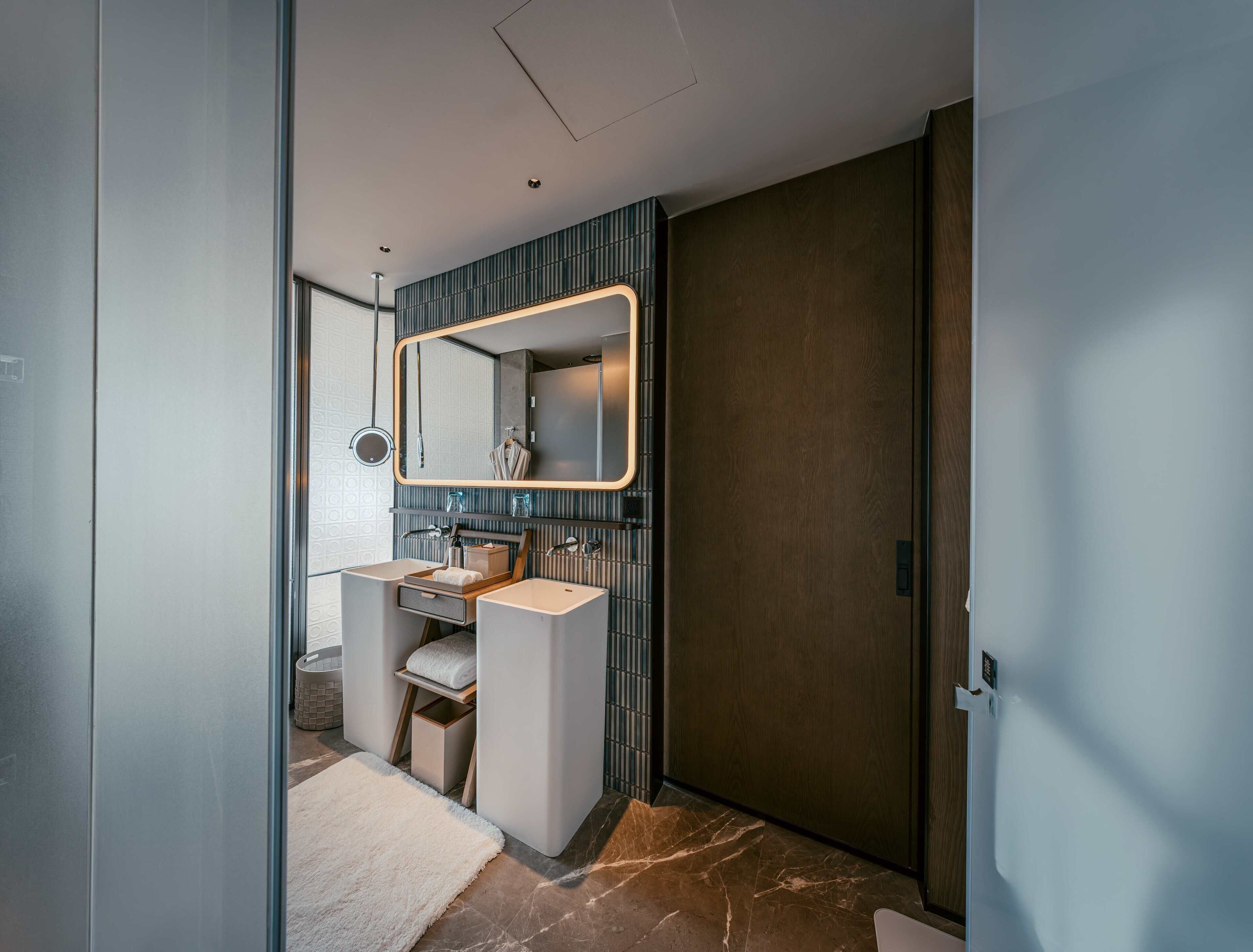 Un bagno moderno con uno specchio grande, due lavandini e un porta asciugamani.