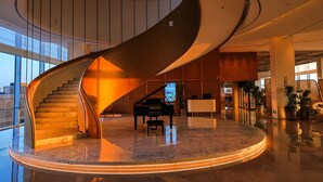 A grand lobby with a spiral staircase, a grand piano, and a reception desk. - Nousland Beijing (Tongzhou)