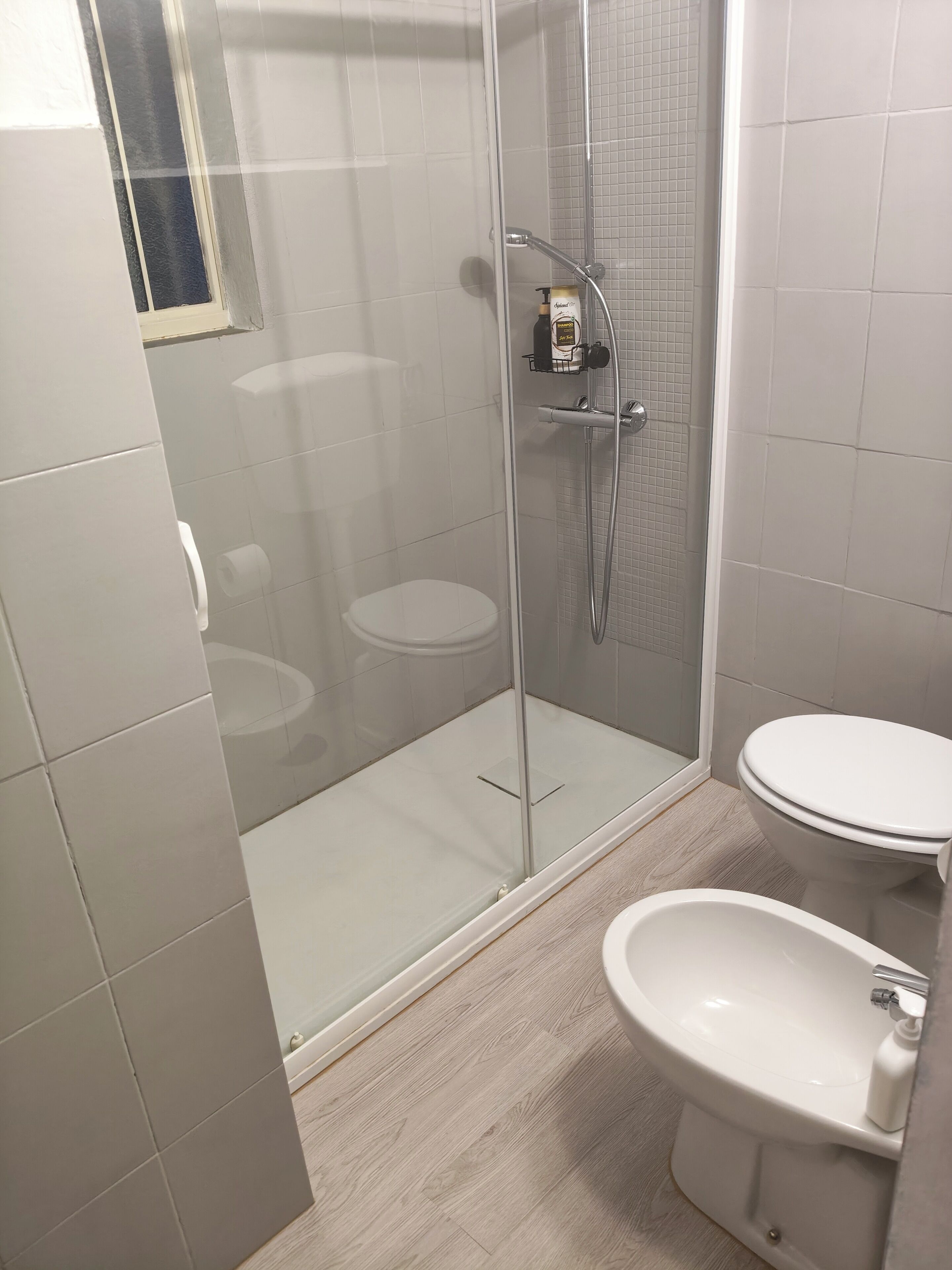 A bathroom with a glass-enclosed shower, a toilet, and a sink.