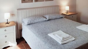 A bedroom with a bed, two bedside tables, a wall-mounted lamp, and a radiator. - La Voltina – The ideal starting point for exploring Lucca and the Garfagnana (Diecimo)