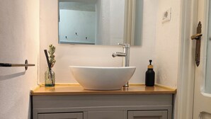 A bathroom with a white sink, a mirror, a towel rack, and a cabinet with drawers. - La Voltina – The ideal starting point for exploring Lucca and the Garfagnana (Diecimo)