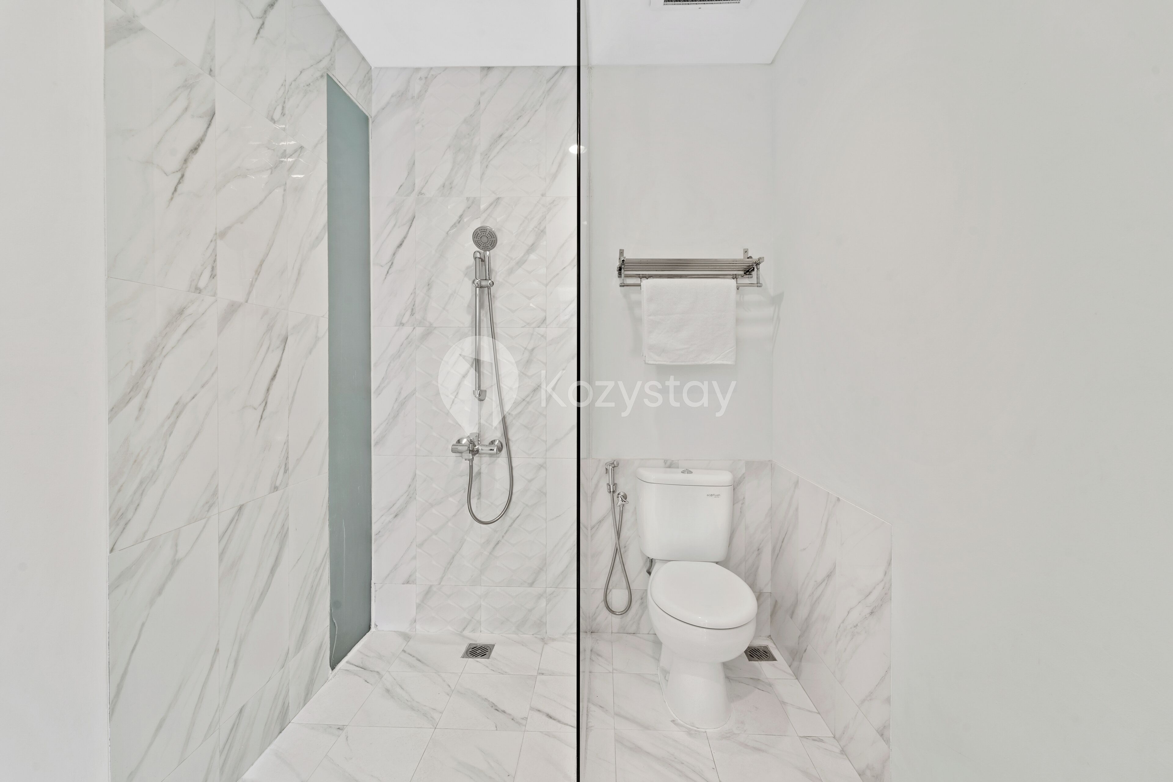 Een moderne badkamer met een glazen douchewand, een toilet en een handdoekhouder.
