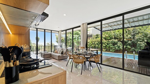 A modern kitchen with a dining area, large windows, and a pool view.