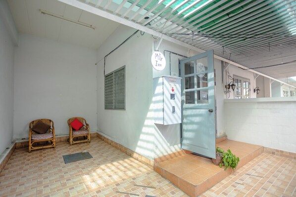 A room with two wicker chairs, a check-in station, a door, and a tiled floor. - Mitr Inn Hua Hin Beach (Hua Hin)