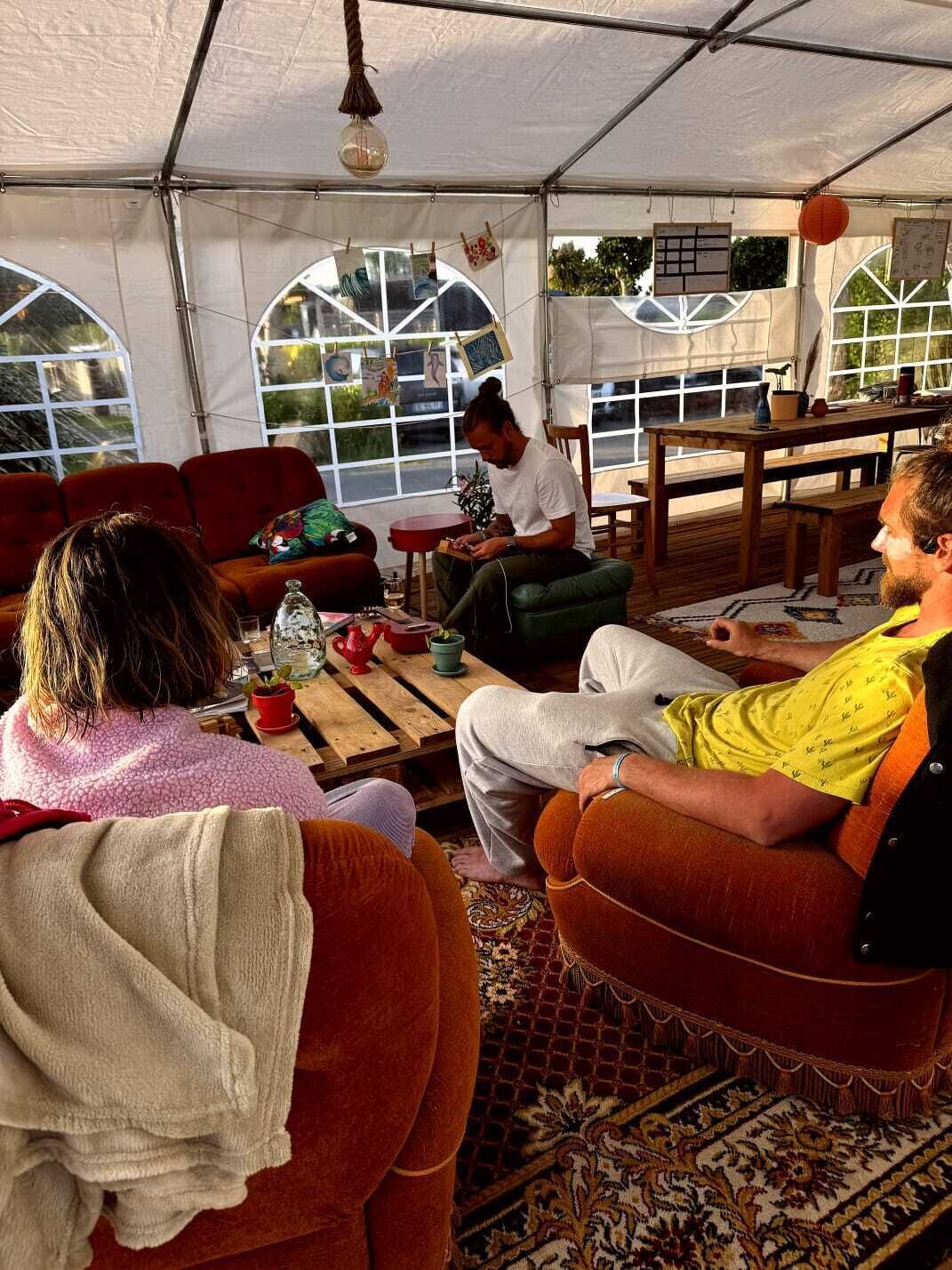 Un espacio con carpas, una mesa, sillas y una persona trabajando en un ordenador portátil.