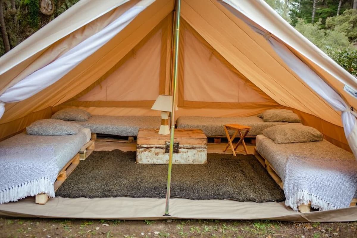 A tent with two sleeping areas, a central table, and a small stool.
