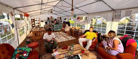 A tented accommodation with a central dining area, multiple seating options, and large windows.
