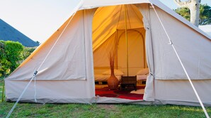 A large tent with a red carpet inside, a wooden bench, and a tall vase. - The Glamping Spot - Penmarch  (Penmarch)