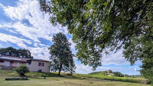 A picnic table in a grassy area with a house in the background. - Window on castle (Monflanquin)