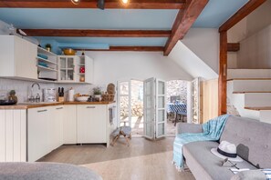 A modern kitchen with white cabinets, a wooden ceiling, and a dining area with a grey sofa and a table. - La Rocca Duo - Hidden In Istria (Rasa)