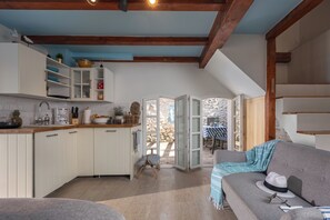 Una cocina acogedora con armarios blancos, techo de madera y vistas a un patio exterior.