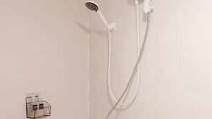 En bruser med brusehoved, der kan holdes i hånden, og et kontrolpanel på væggen.
