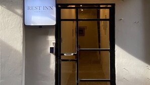 En bygningseingang med et skilt der siger "REST INN" og en grøn markise over døren.