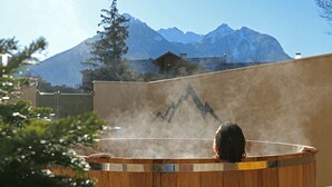 A person in a wooden hot tub with steam, surrounded by a mountain backdrop. - Garrigae Caserne de Briançon & Spa - les Cinq Mondes (Briançon)