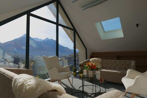 A modern living room with large windows, a sofa, a coffee table, and a view of mountains. - Garrigae Caserne de Briançon & Spa - les Cinq Mondes (Briançon)